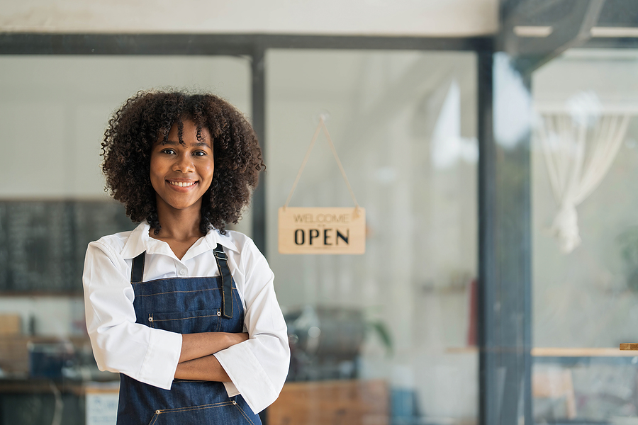 Business owner in front of an open for business sign