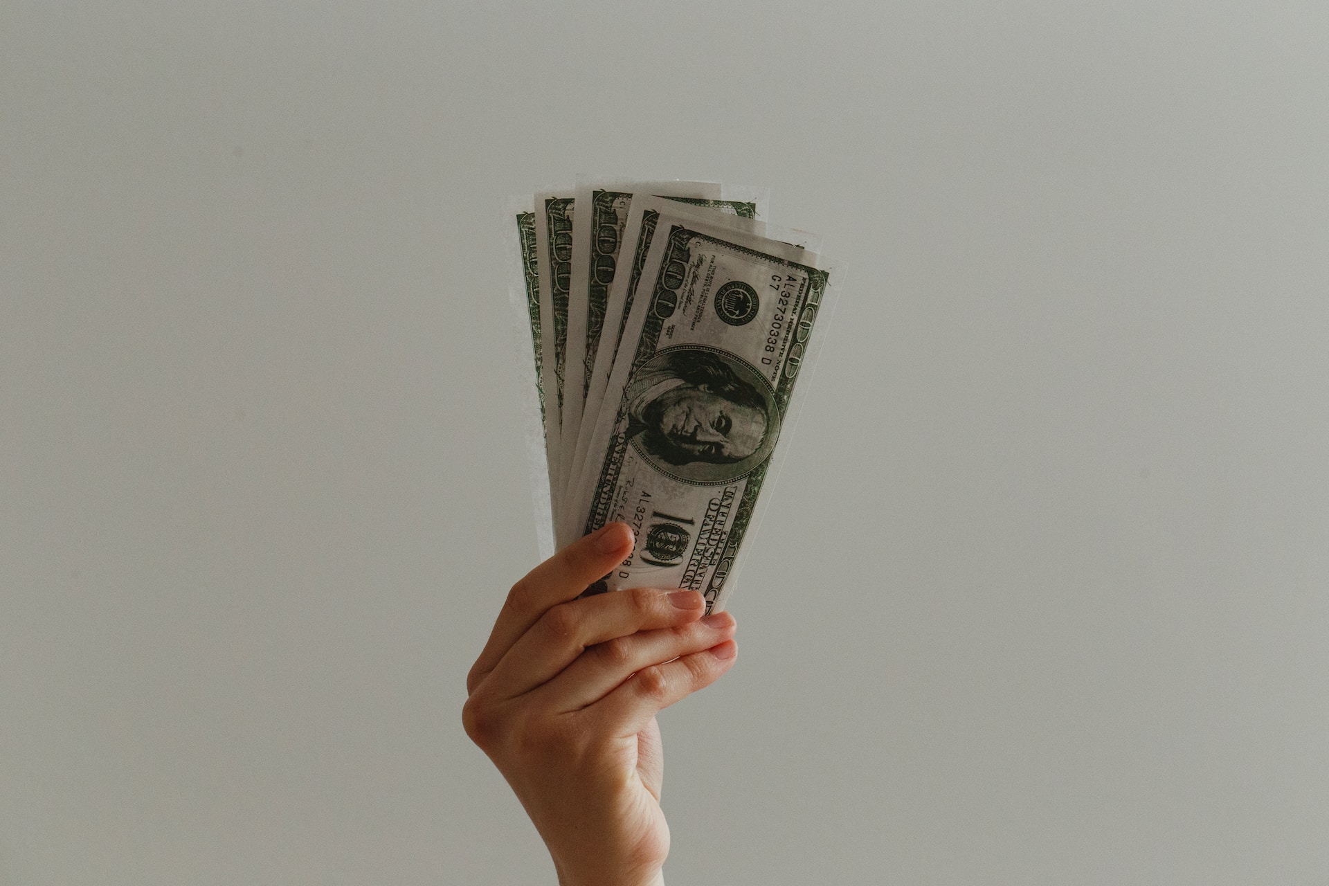 Person holding a bunch of $100 bills in their hand